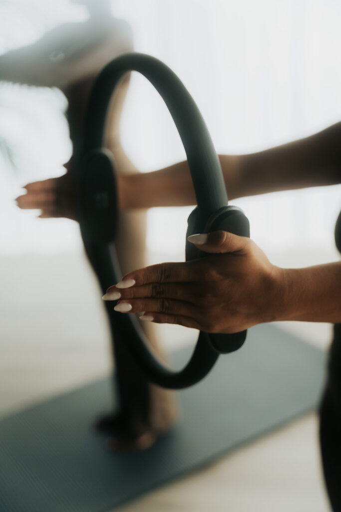 Close-up van handen die pilates ring vasthouden tijdens oefening, beweging in beweging gevangen met zachte onscherpte, mindful movement in de studio.